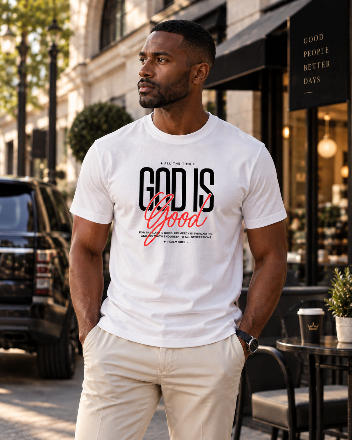 Man wearing a white 'God Is Good' Psalm 100:5 t-shirt on a city street outside a cafe